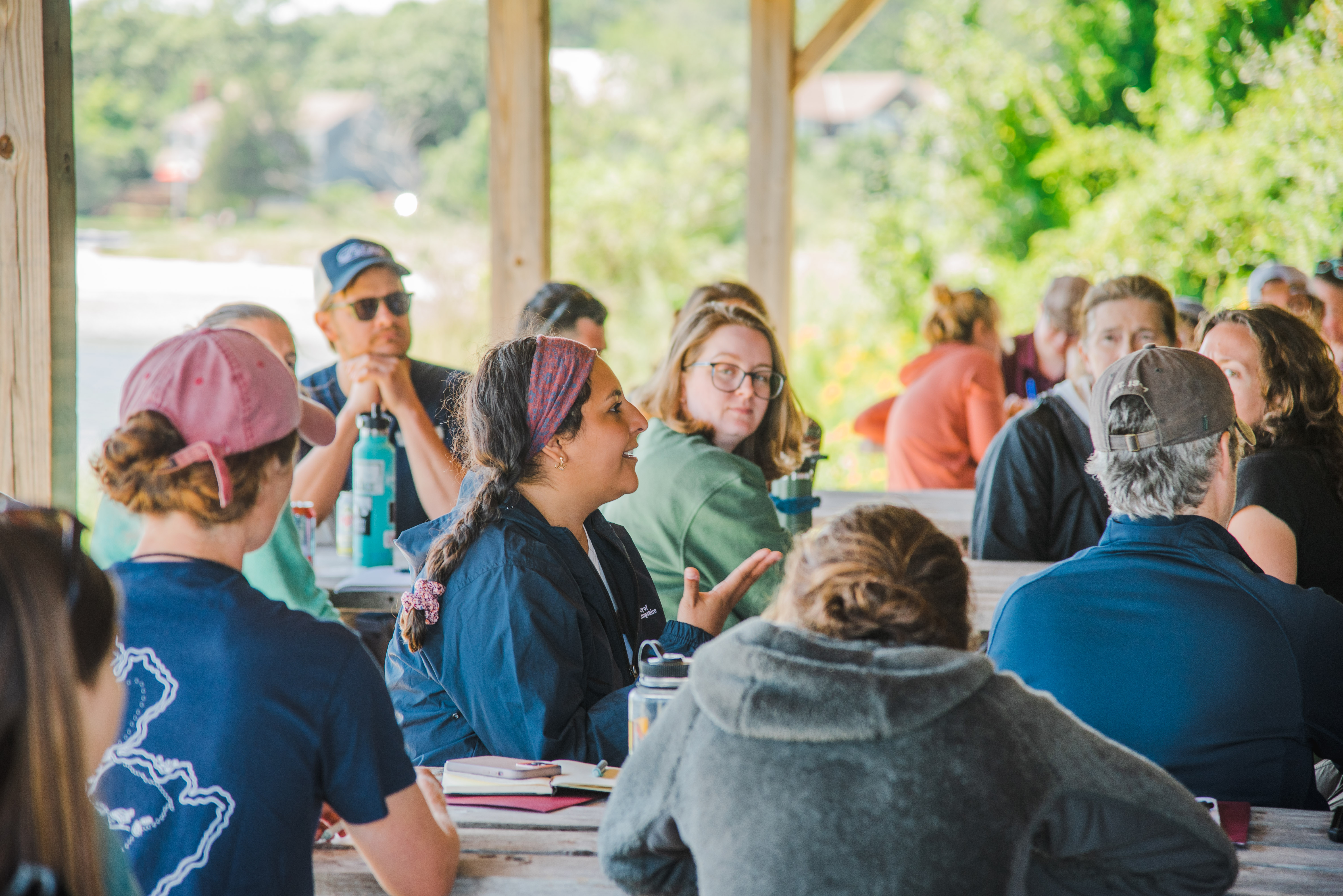 A group of CoastWise participants sits at picnic tables, discussing a coastal topic.