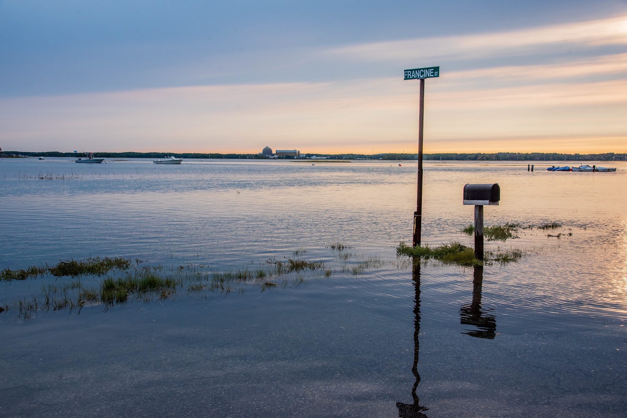 An image of a flooded street in Hampton, NH with a street sign and mailbox in the water.