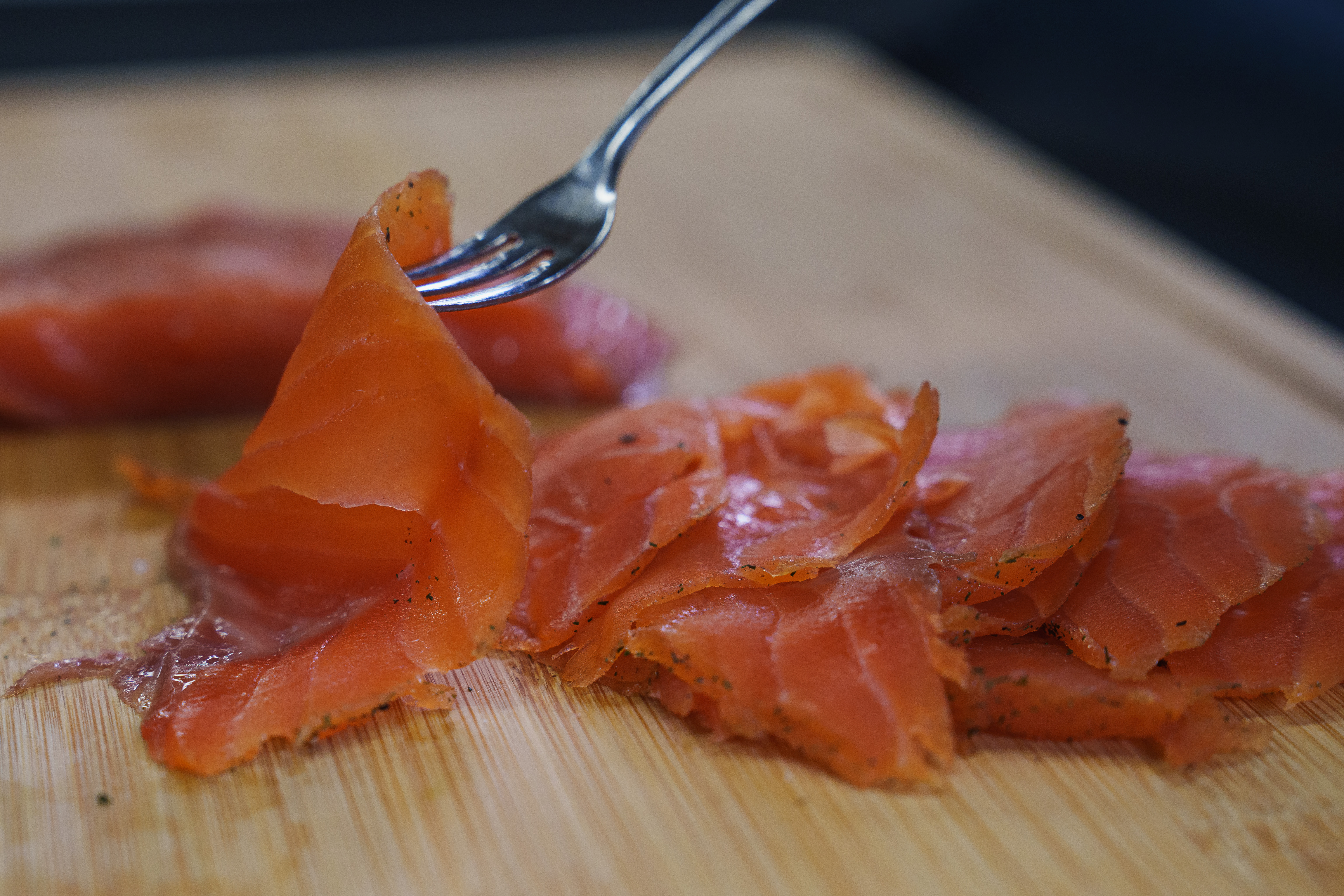 Cured trout on a cutting board with a fork taking a bite.