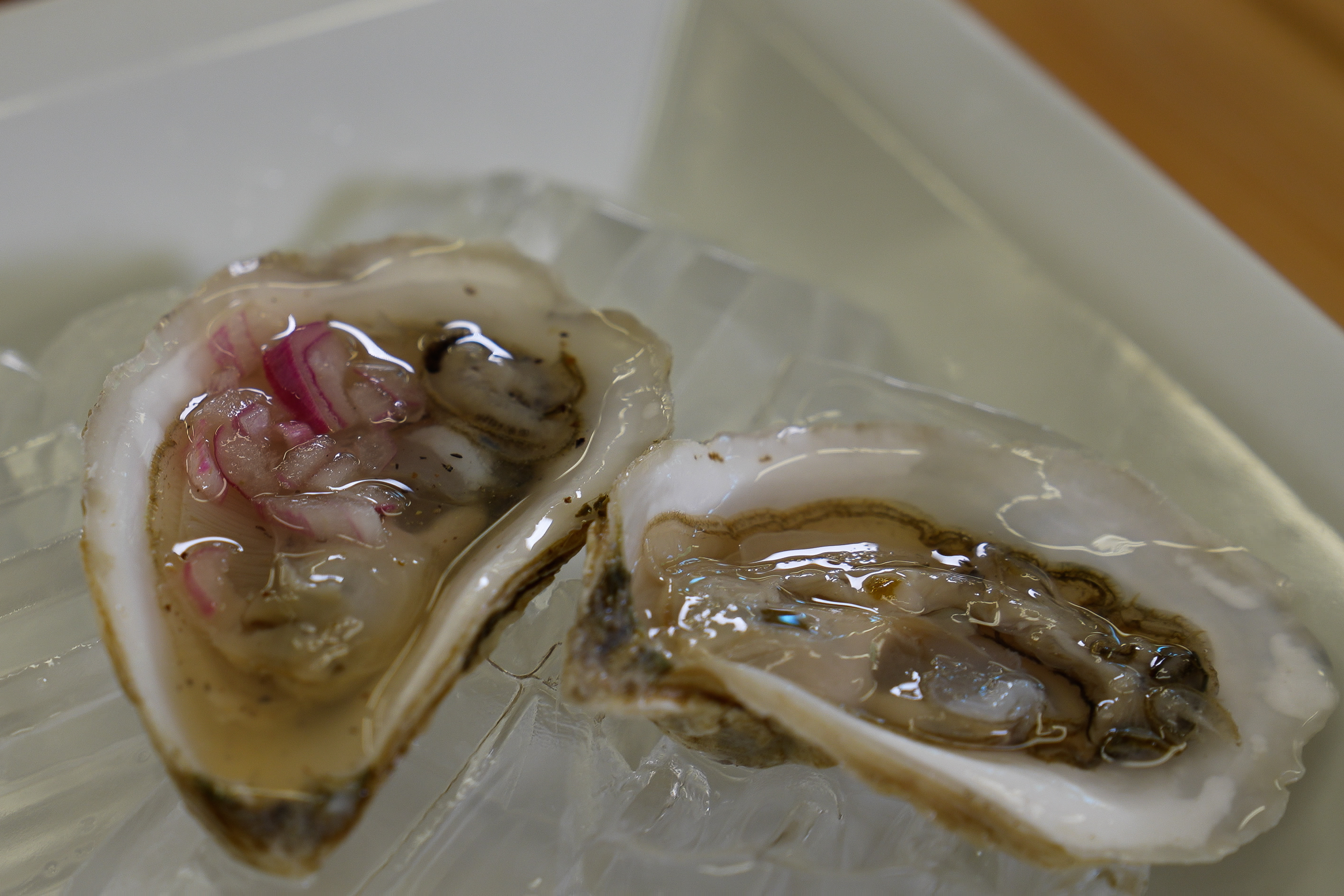 Two oysters with ginger beer mignonette on ice.