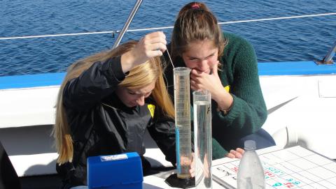 Students using graduated cylinders on a boat