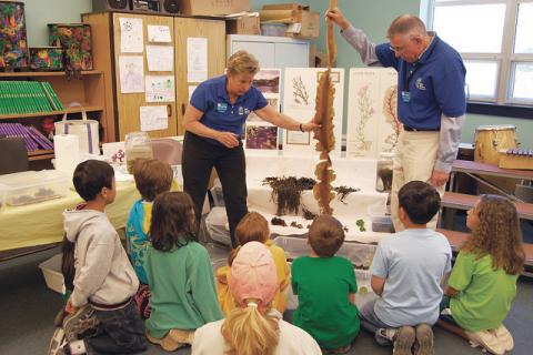 Marine Docents holding kelp in front of a class of young students