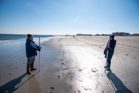 people taking measurements on a beach