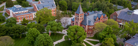 aerial photo of UNH's iconic Thompson Hall with flagpole, surrounding buildings, and green trees