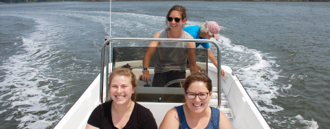 Three young women participating in Sea Grant's Doyle Fellowship program steer a boat across Great Bay to conduct oyster research in the summer.