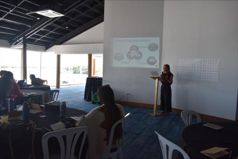 Knauss Fellow Natalie Lord presents at a lecture in front of a seated audience with a powerpoint presentation in Spanish