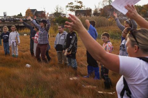 A group of students in a circle learning about the salt marsh by dancing. 