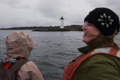 Two participants look at Portsmouth Harbor Lighthouse from the vessel. 