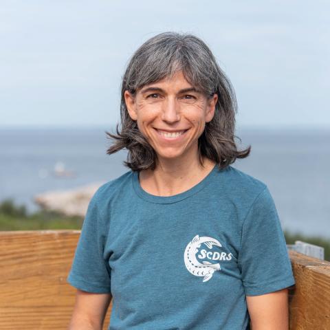 Lynn Vaccaro headshot photo with the ocean in the background.