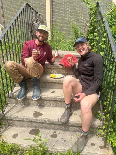 Emma sits on steps with her mentor, Linas Kenter, enjoying some shucked oysters.