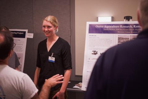 Emma presents a poster with her summer's work at the Doyle Fellowship celebration. 