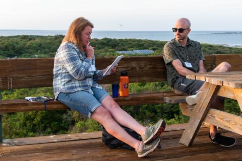 Two CoastWise participants sit together on Appledore Island, discussing work.