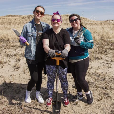 A group of 3 women pose together with their gardening equipment at the Common Garden. 