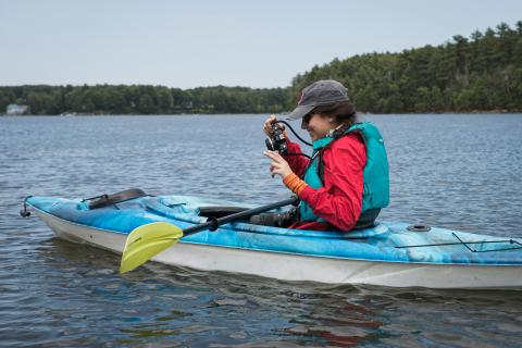 Doyle Fellow Talia looks at her photos while kayaking.