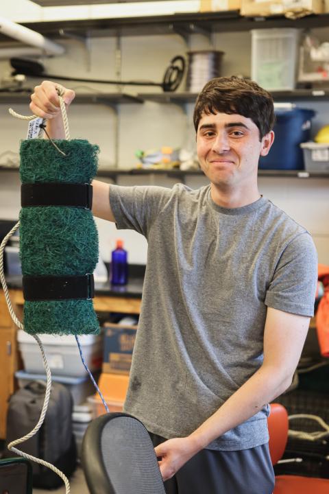 Doyle Fellow Jacob holds up his sampling gear, smiling for the camera.