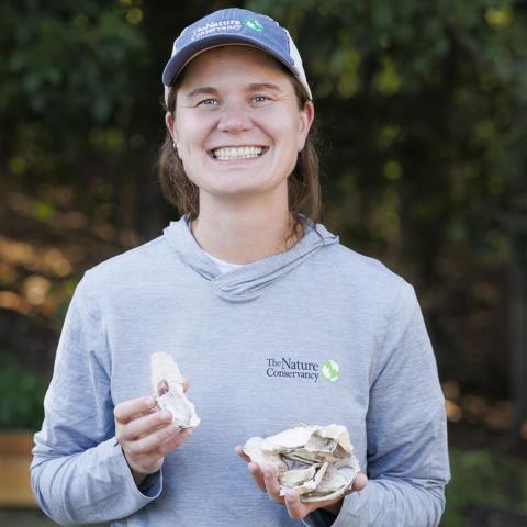 A headshot photo of Kelsey Meyer-Rust holding an oyster. 