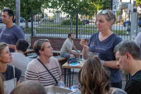 Laura Brown speaks to a group of participants, explaining how to shuck an oyster.